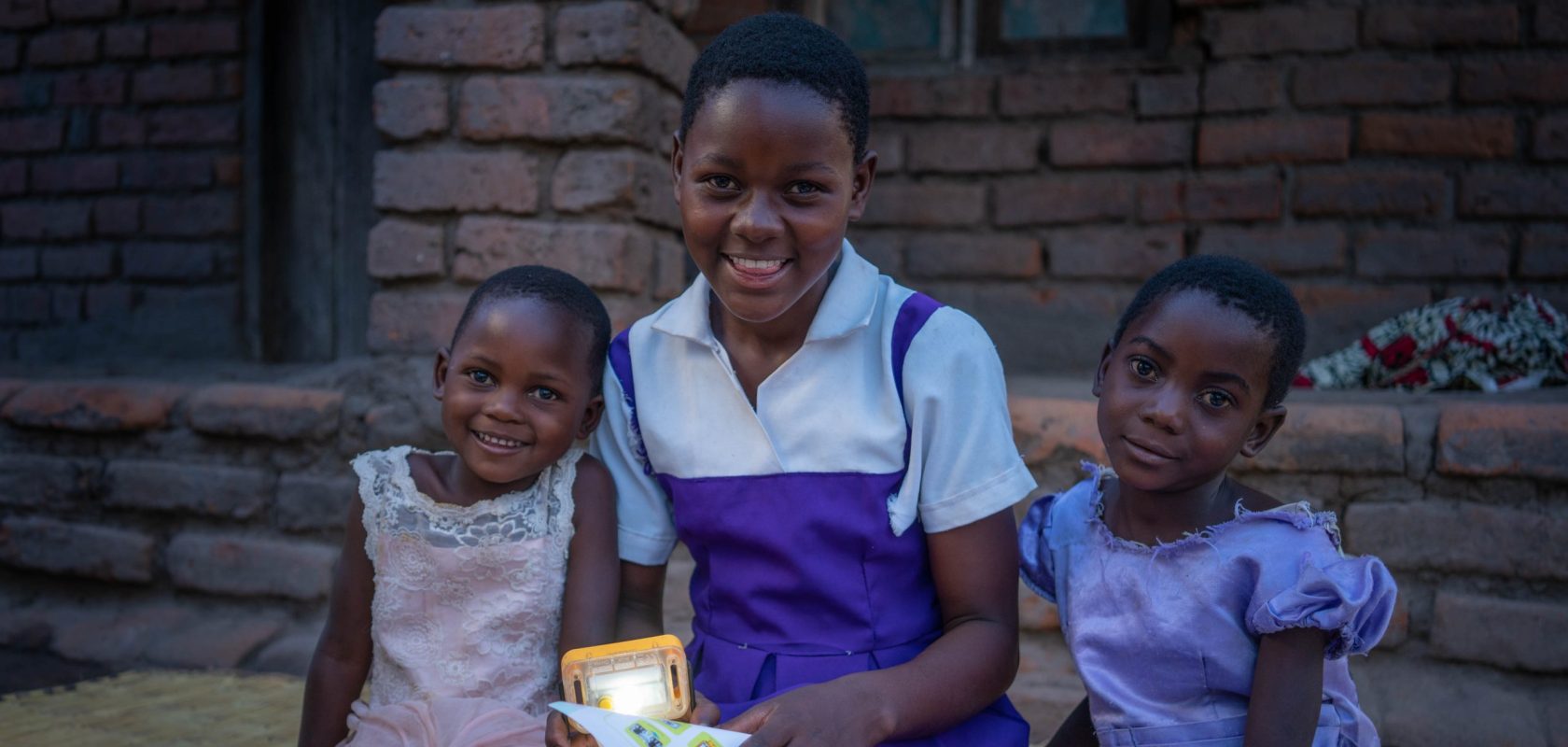Three girls read with a solar light.