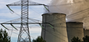 Overhead electricity powerline, with two coal smoke stacks in the background. 