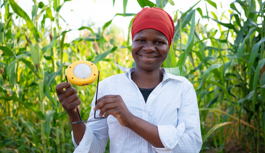 Liness Friday holds her solar light proudly and looks to camera.