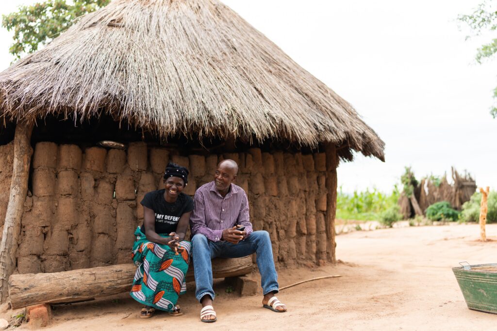 Fridah Luputa Mwale and her husband sitting outside their home in Chipungu village, Zambia.